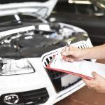 Car mechanic holding clipboard in a garage