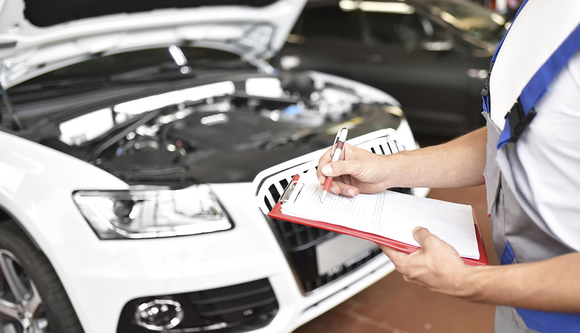 Car mechanic holding clipboard in a garage